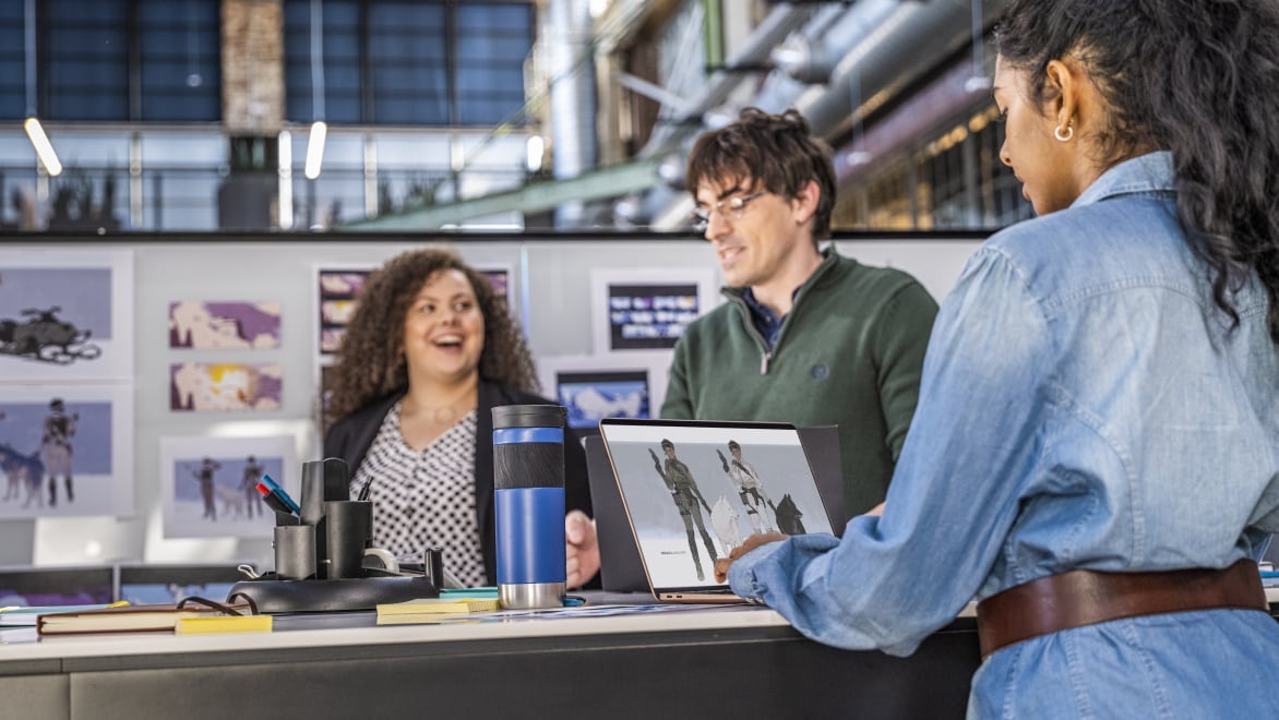 Three people around a desk with a laptop